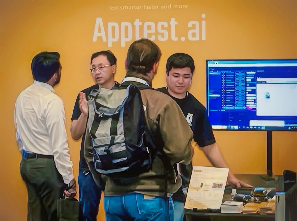 Visitors talking with staff at the Apptest.ai exhibition booth.