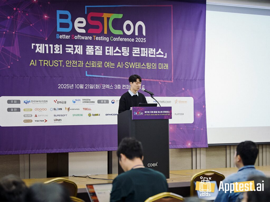 보라색 BeSTCon 2025 행사 배너(“제11회 국제 품질 테스팅 콘퍼런스”, “AI TRUST…”) 앞에서 연사가 마이크가 있는 단상에 서서 발표하고, 앞자리 청중이 앉아 있는 장면 (우측 하단 Apptest.ai 워터마크)